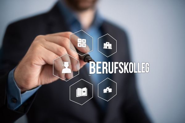 Das Bild zeigt einen Mann mit Stift der auf das Wort Berufskolleg zeigt