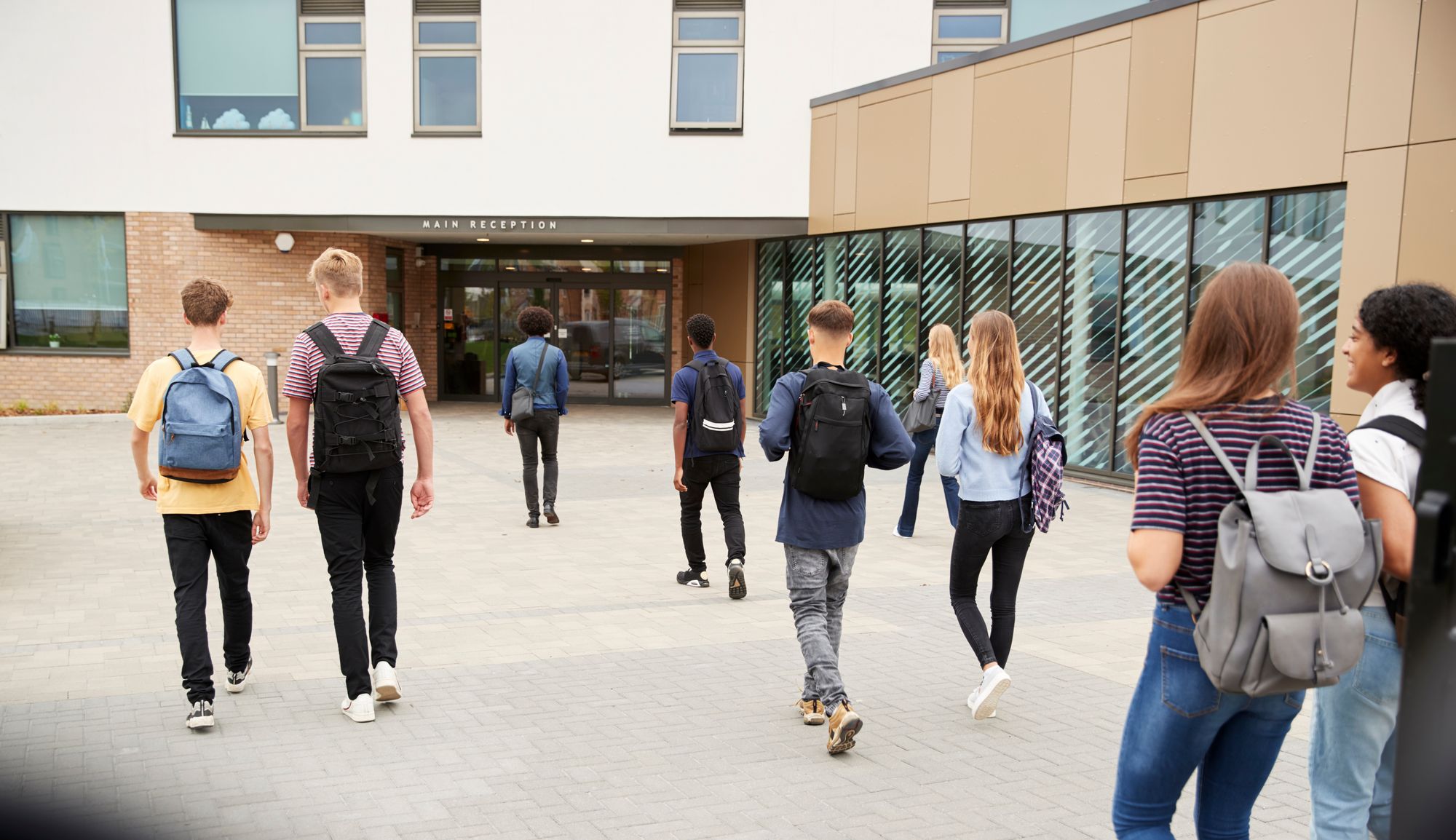 Bild zeigt Schüler die in ein Schulgebäude reinlaufen